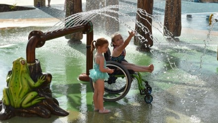 two little girls playing in the waterpark, one is in a wheelchair