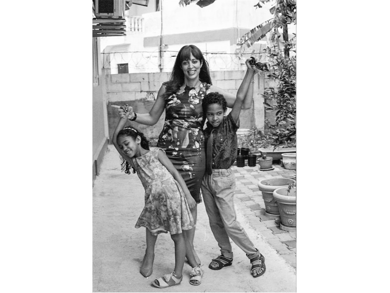 a mom and her son and daughter dressed up and walking down the street pose for a photo