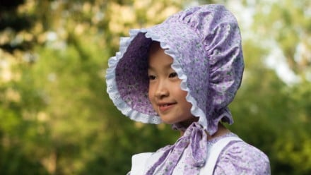 A little girl dressed in an old-fashioned bonnet and dress