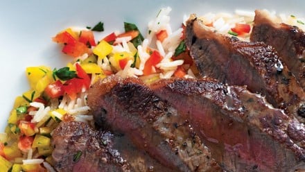 medium-rare steak on top of a red and yellow pepper pilaf