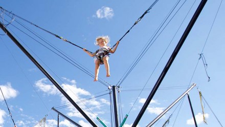 Kid riding the Kiss the Sky Bungy trampoline at the Family Adventures Zone at Whistler Blackcomb in BC