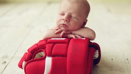newborn baby posed with a hockey mit