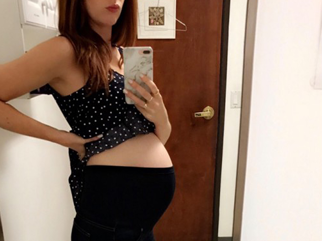 Pregnant woman takes a mirror selfie of her baby bump