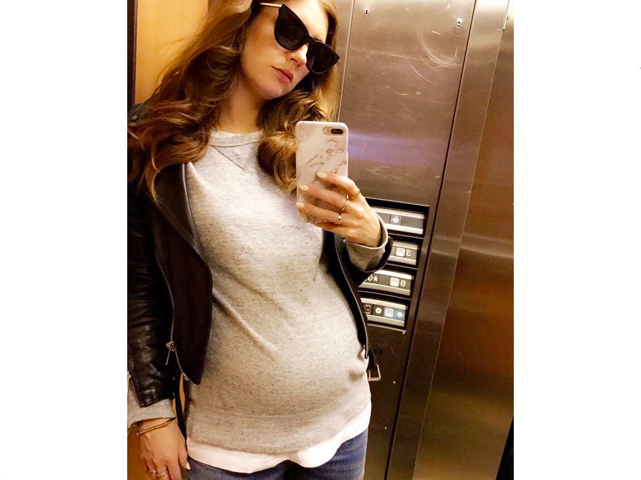 Pregnant woman takes a mirror selfie in an elevator