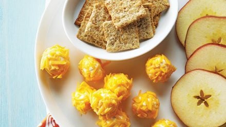 plate with small cheese balls, crackers and apple slices