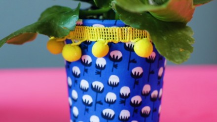 planter covered in blue fabric with yellow pompom tassel