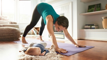 Mother does yoga while keeping an eye on her newborn baby