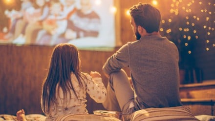 Dad and daughter watching a movie on a projector outside