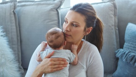 worried mother holds newborn baby close