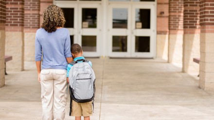 Mom and son stand in front of school