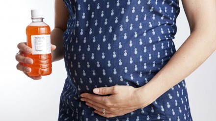 Pregnant woman holding liquid for glucose test