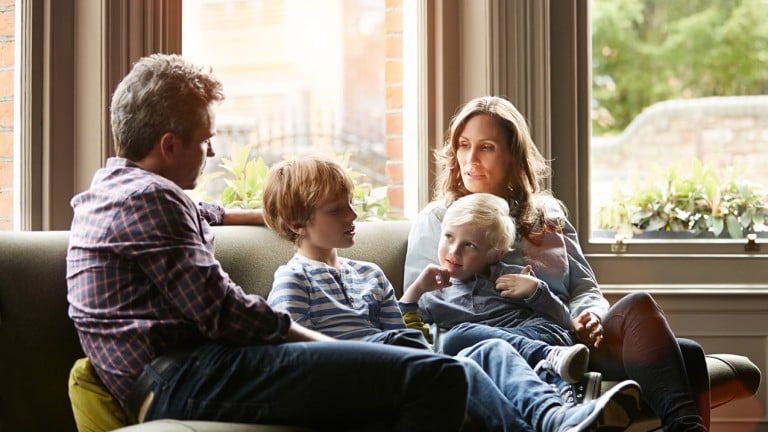 Shot of a family of four sitting together on their living room sofa - how to talk to your kids about racism