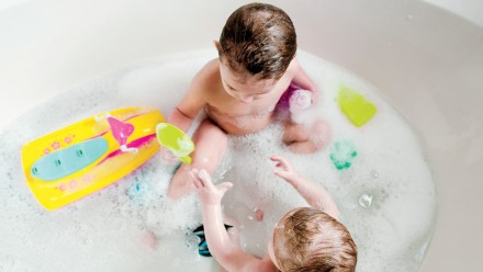 two babies in the bath with tub toys