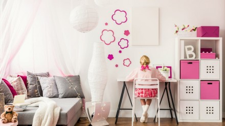 little girl sits at desk in white and pink sensory-friendly bedroom