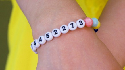 A little hand wearing a bracelet with beaded numbers on it