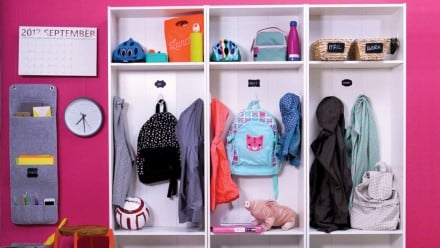 A front entryway with three bookcases and organized jackets, backpacks, etc