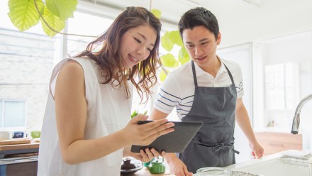 Young couple in the kitchen looking at a tablet
