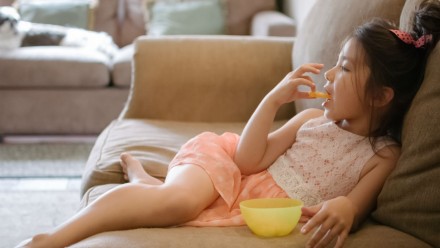 little girl eating snack on couch