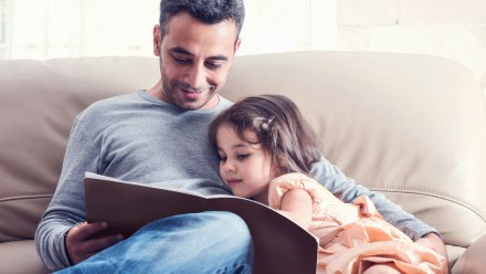 Father and daughter reading on a sofa