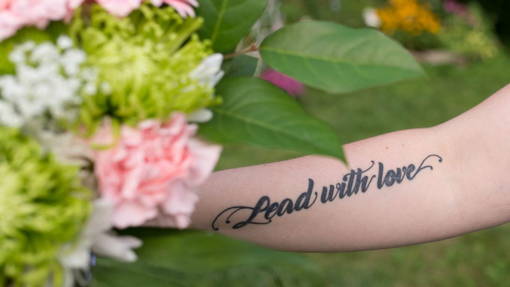 Photo of a tattoo that says "lead with Love"
