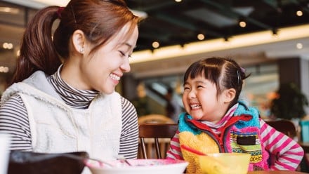 Mother and daughter sitting at a cafe laughing and smiling