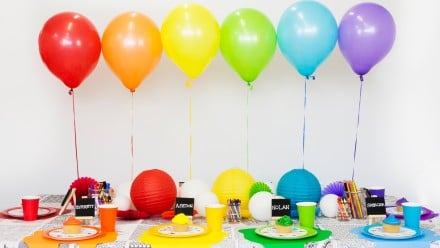 Colourful table spread for an art-themed party with balloons, lanterns and mini easels for name cards