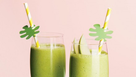 two glasses with green smoothie garnished with green apple