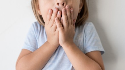 Child with her hands covering her mouth