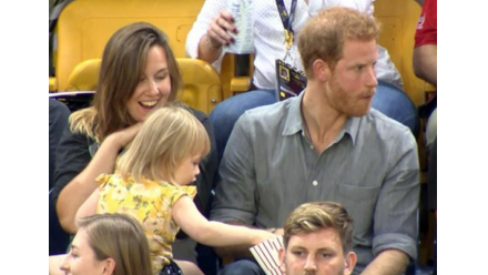 little girl stealing popcorn from Prince Harry's lap