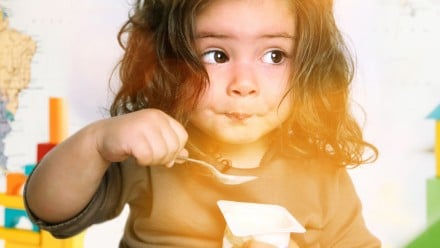 little girl eating yogurt at school