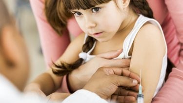 Close up of a cute little girl at the doctor's who's scared of getting a flu shot vaccine