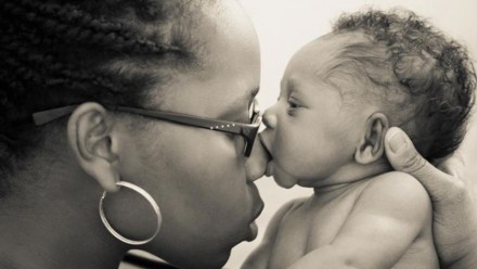 Woman with newborn baby kissing her nose
