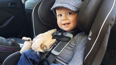 baby boy sitting in car seat smiling