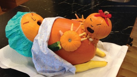 pumpkin carved as pregnant woman wearing hospital scrubs and giving birth