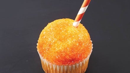 A cupcake decorate like an orange snow cone