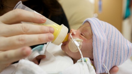 premature baby being fed breast milk from a bottle