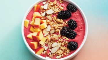 raspberry smoothie with cut up fruit and granola