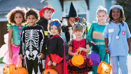 A group of kids standing outside wearing halloween costumes