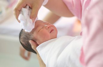 Newborn baby getting head cleaned