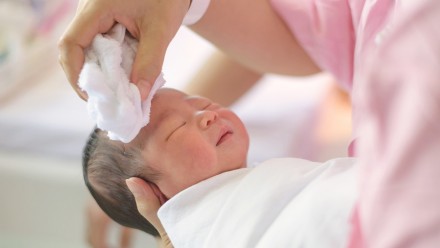 newborn baby getting his head cleaned with a towel
