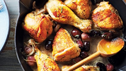Cast iron pan with braised chicken thighs and legs with grapes, olives and rosemary