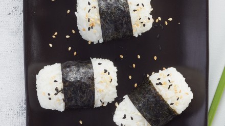 Black plate with rice rolled in seaweed and sprinkled with sesame seeds
