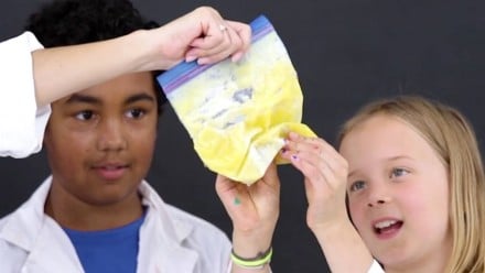 A young girl looking at a ziplock bag filled with a yellow substance