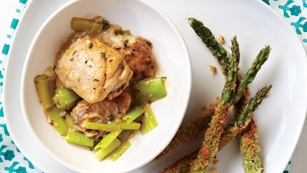 Chicken thighs sitting on sautéed leeks with breaded asparagus fries on the side