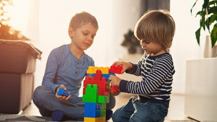 two boys playing with blocks in a sunbeam