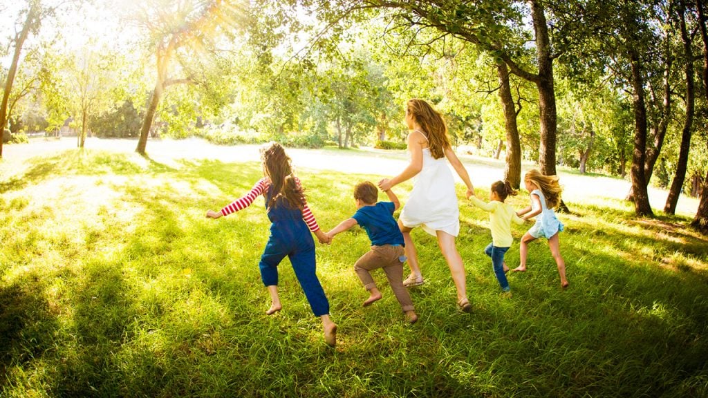 Family with four kids running through a field