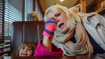 little kid putting their foot on the table and their mom looking horrified