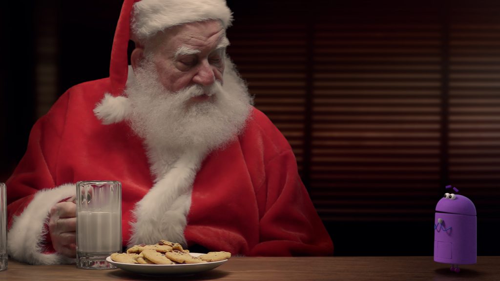 Screenshot from A StoryBots Christmas showing Bo, a purple storybot talking to Santa as Santa drinks milk and eats cookies