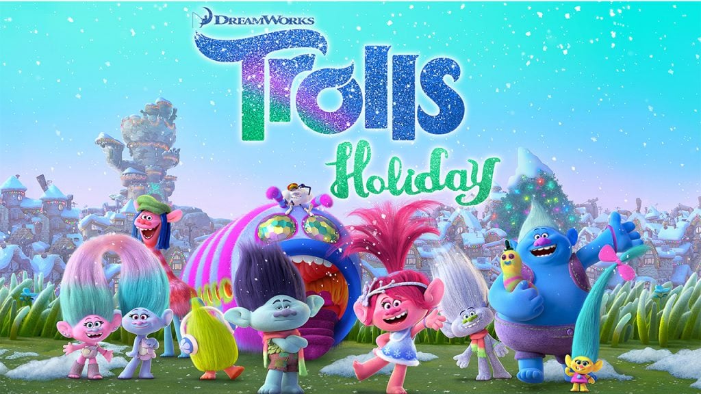 Promo image for the Trolls Holiday Special shows the characters from the Trolls movie standing in a field with glitter everywhere
