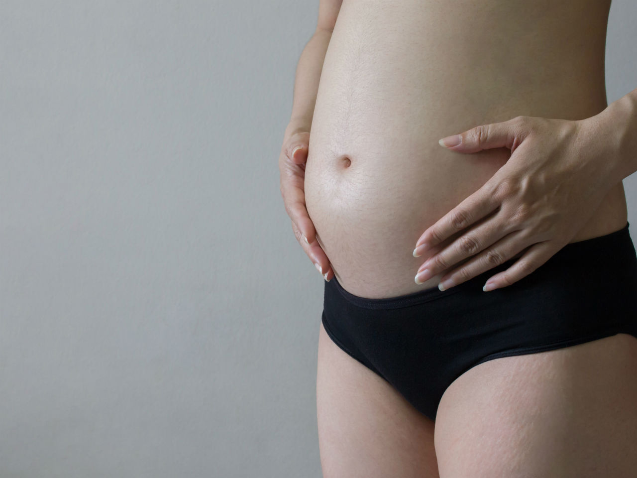 Pregnant woman holding her bare belly